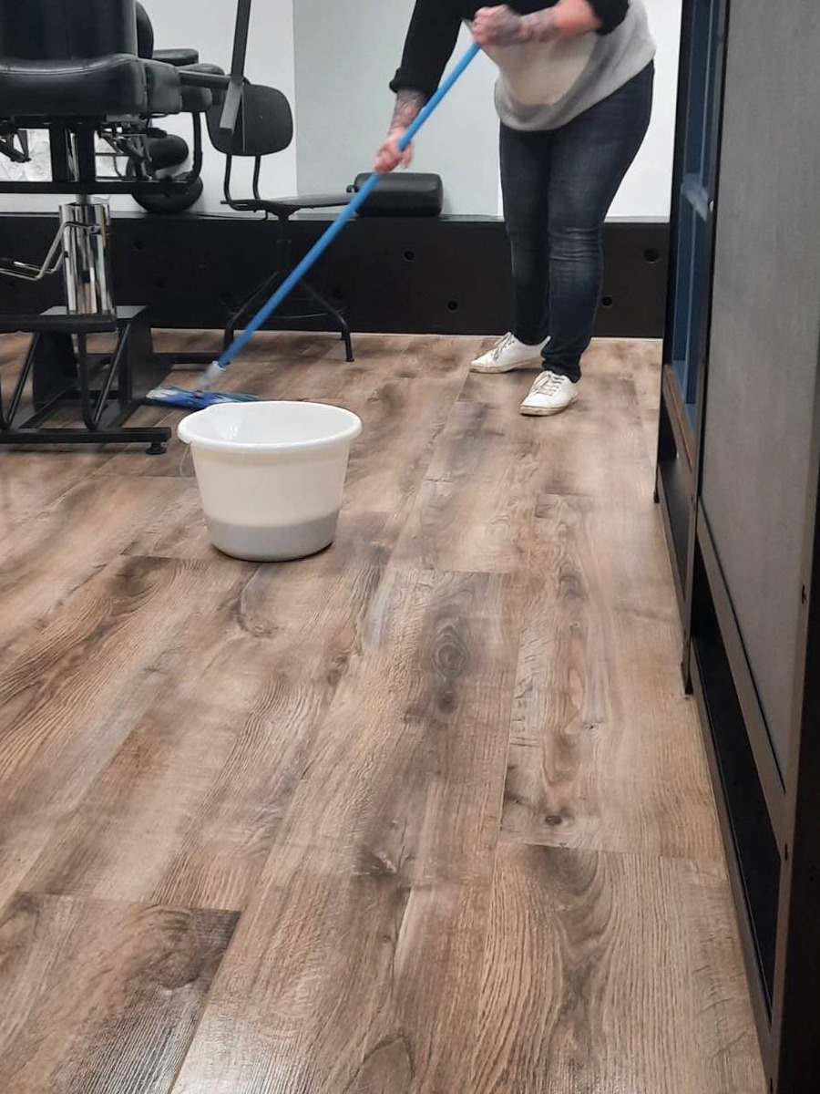 Een vloer wordt gedweild in een studio, met emmer en dweil
