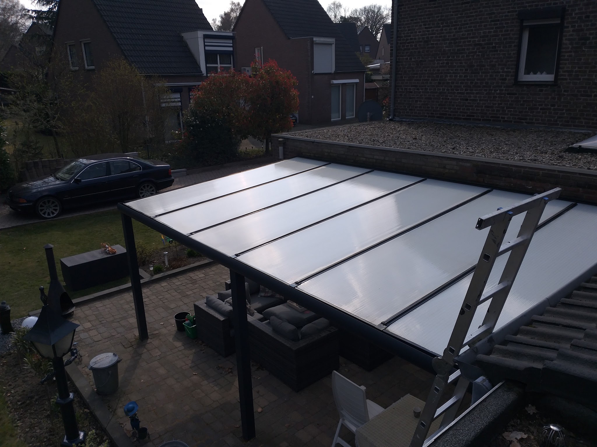 Polycarbonaat overkapping van boven gezien, met een ladder tegen het dak
